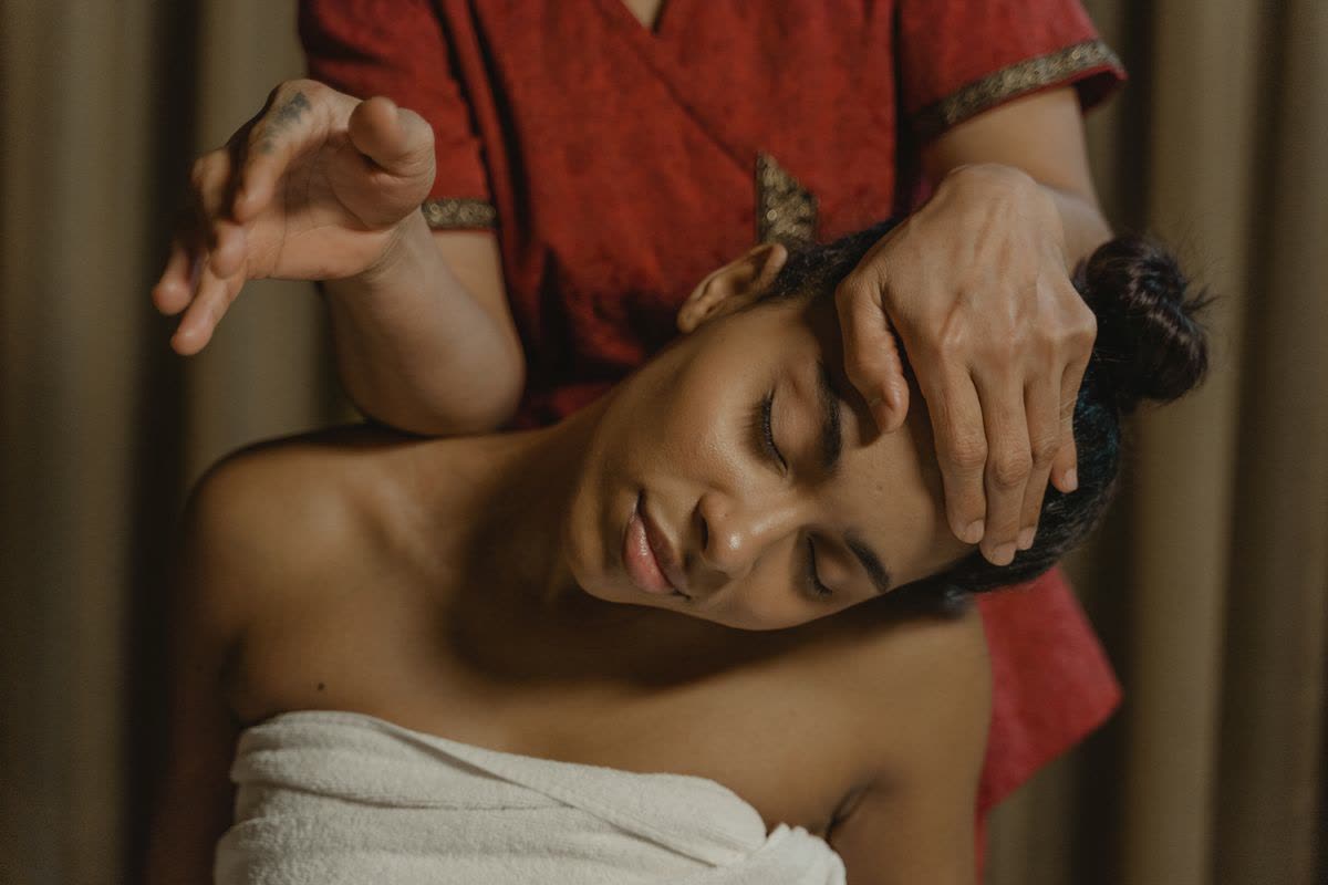 Therapist giving a relaxing head and face massage in a dark luxury spa room