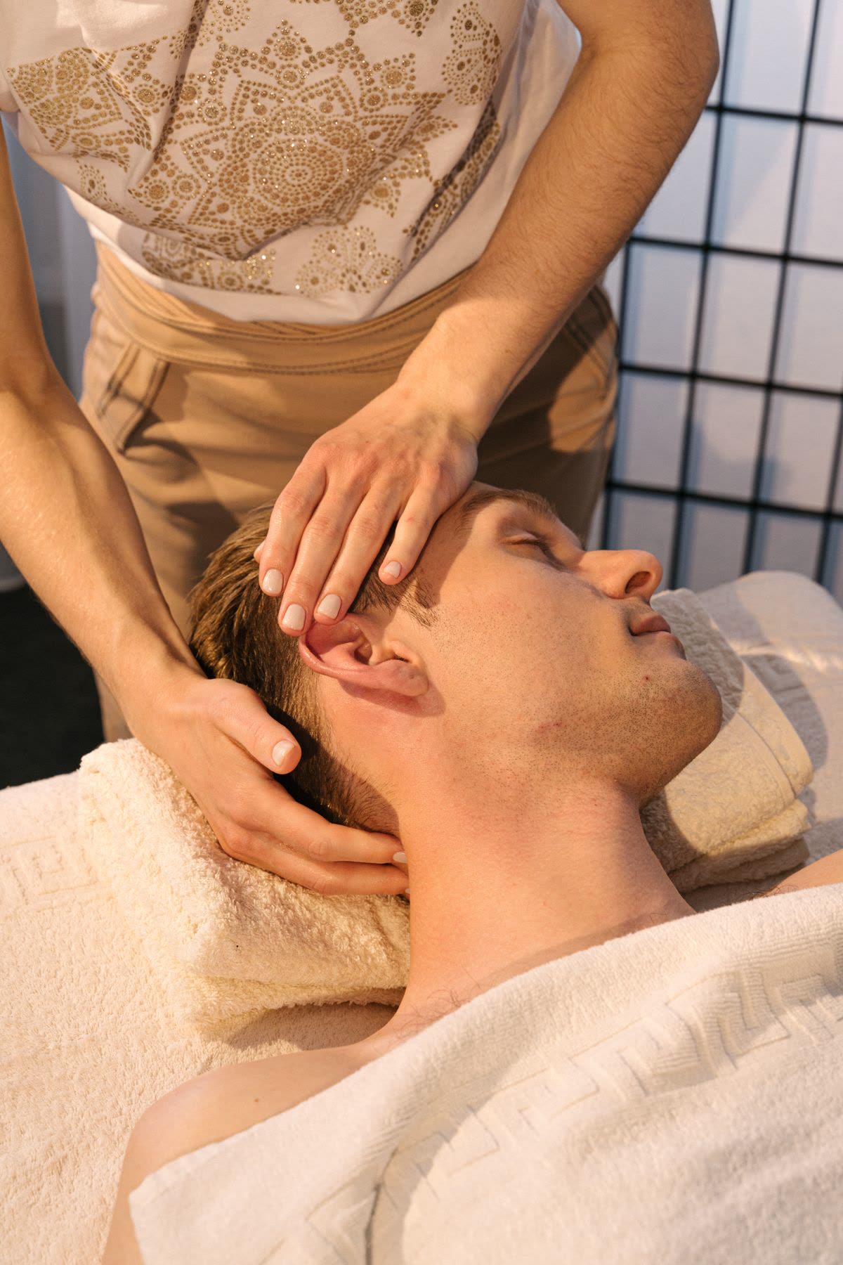 Male client receiving a calming head massage on a spa treatment table