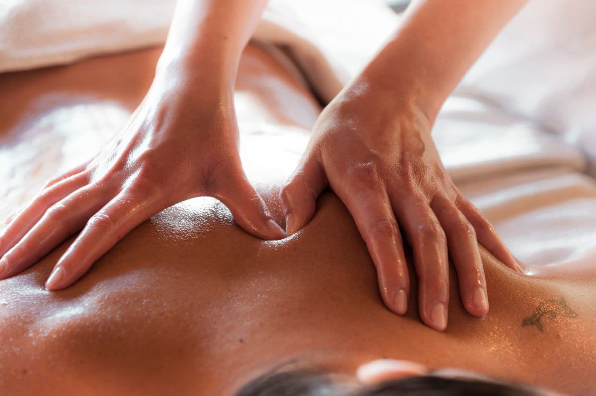 Hot oil being massaged into the back of a client during a spa treatment